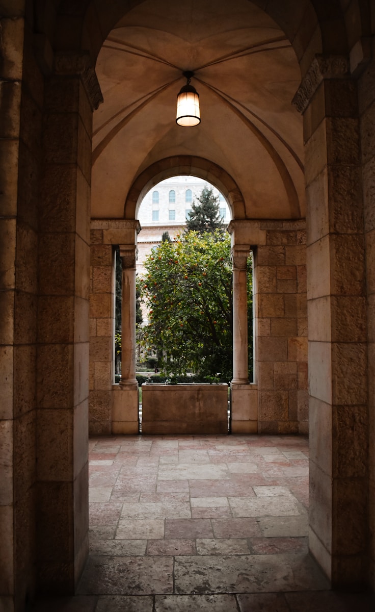 an archway leading into a building with a clock tower in the background